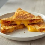 air fryer cheese quesadilla: Golden crispy air fryer cheese quesadilla with melted cheese oozing from the cross-section.