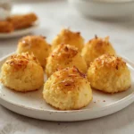 air fryer coconut macaroons: Golden brown crispy coconut macaroons stacked on a plate, showing chewy interior texture.