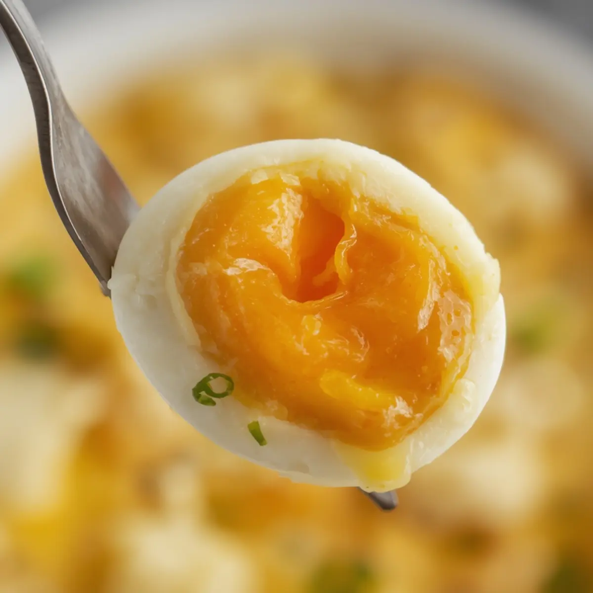 Air Fryer Soft Boiled Eggs: Air fryer soft boiled eggs cut in half showing a creamy jammy yellow yolk and tender white on a dark surface.