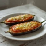air fryer stuffed eggplant: Air fryer stuffed eggplant with melted mozzarella and golden parmesan crust, resting in an air fryer basket