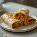 Air Fryer Breakfast Burrito: Golden crispy air fryer breakfast burrito with melted cheese and fluffy eggs visible inside.