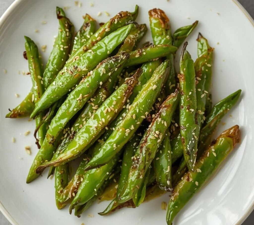 A close-up view of perfectly cooked air fryer sugar snap peas, garnished with sesame seeds.