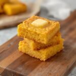 A warm stack of golden Air Fryer Cornbread topped with melting butter on a board